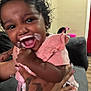 Adore is registered to the contest to win money with this photo: baby, child, milk_mustache, laughing, happy, curly_hair, pink_clothing, tattoo, hand, person, indoor, sofa, living_room, blur, cute, smiling, infant, holding, skin, human