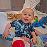Franklin joined the competition — help win amazing prizes! baby, child, smiling, happy, indoor, toy, cat, orange_cat, blanket, playpen, clothing, infant, cute, sitting, head, face, furniture, home, pet, colorful