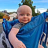 baby, baby_carrier, blue_sky, child, clothing, daylight, expression, face, hand, happy, head, house, infant, nature, outdoor, person, playful, smiling, suburban, tree