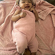 Sixx is registered to the contest to win money with this photo: baby, blanket, bow, child, close_up, couch, cozy, cute, face, fashion, happy, headband, indoor, infant, knitwear, lying_down, pink_outfit, portrait, sandals, smiling
