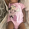 Sixx is registered to the contest to win money with this photo: baby, bed, blanket, brown_skin, cartoon, child, cozy, curly_hair, cute, indoors, infant, lying_down, minnie_mouse, onesie, peaceful, photograph, pillow, pink_clothing, portrait, sleeping