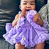 baby, child, infant, smiling, happy, portrait, indoor, couch, seated, lavender_dress, ruffles, white_socks, curly_hair, face, hands, legs, baby_clothing, living_room, cute, photography