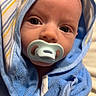 baby, pacifier, blue_towel, hood, striped, infant, close_up, face, eyes, skin, newborn, swaddled, cute, portrait, child, soft_texture, wrapped, indoors, peaceful, looking