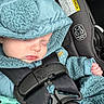 baby, sleeping, car_seat, blue_clothing, hood, bear_ears, seatbelt, infant, close_up, child, safety_label, hand, cute, peaceful, soft_texture, bundle, transport, car_interior, secured, portrait