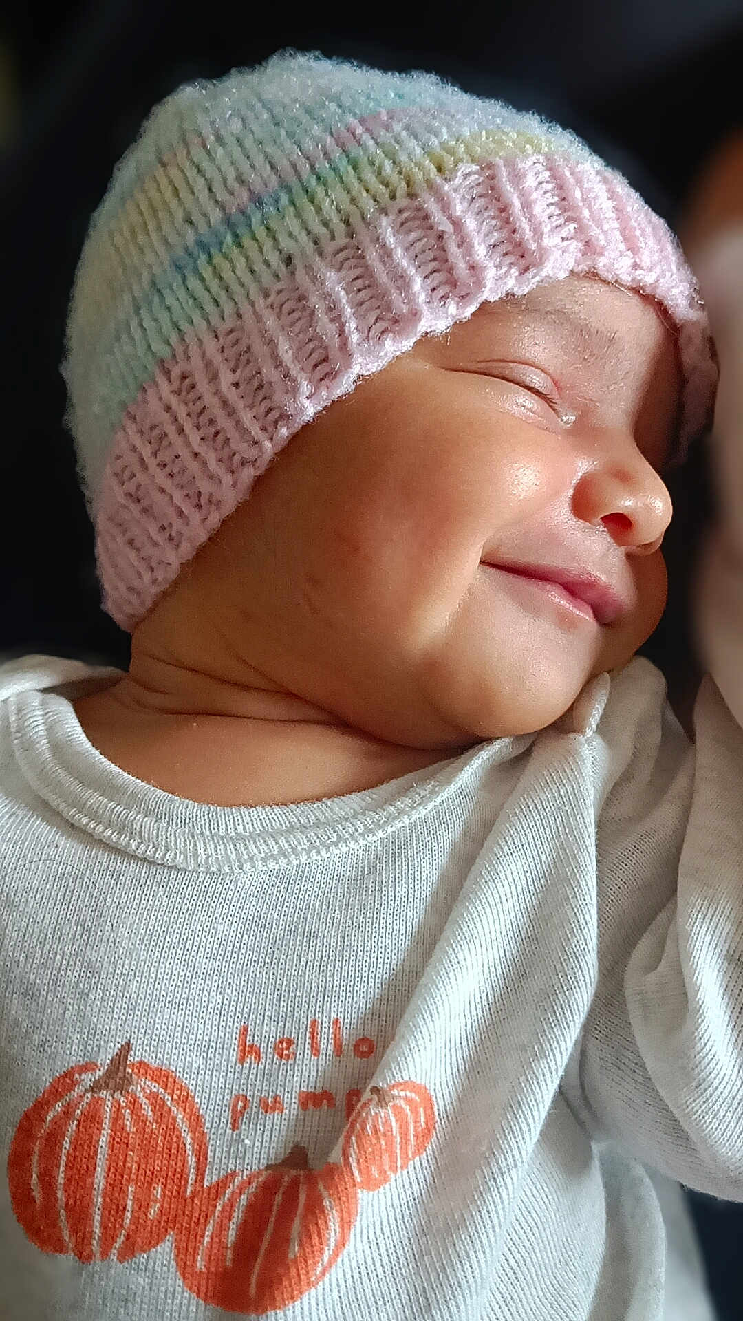 Anaya is registered to the contest to win money with this photo: baby, infant, sleeping, smiling, knit_hat, pastel_colors, white_shirt, pumpkins, cute, peaceful, closeup, portrait, child, apparel, baby_clothes, face, skin, headwear, soft_light, dark_background
