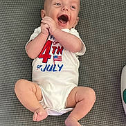 James is registered to the contest to win money with this photo: baby, infant, smiling, clapping, onesie, 4th_of_july, american_flag, celebration, happy, cute, laying_down, mat, barefoot, child, skin, head, arms, legs, mouth_open, joy
