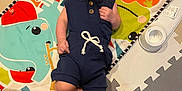 James is registered to the contest to win money with this photo: baby, smiling, romper, play_mat, colorful, musical_instruments, animal_print, indoors, floor_mat, happy, child, infant, person, cute, small, lying_down, toy, playtime, joyful, cozy