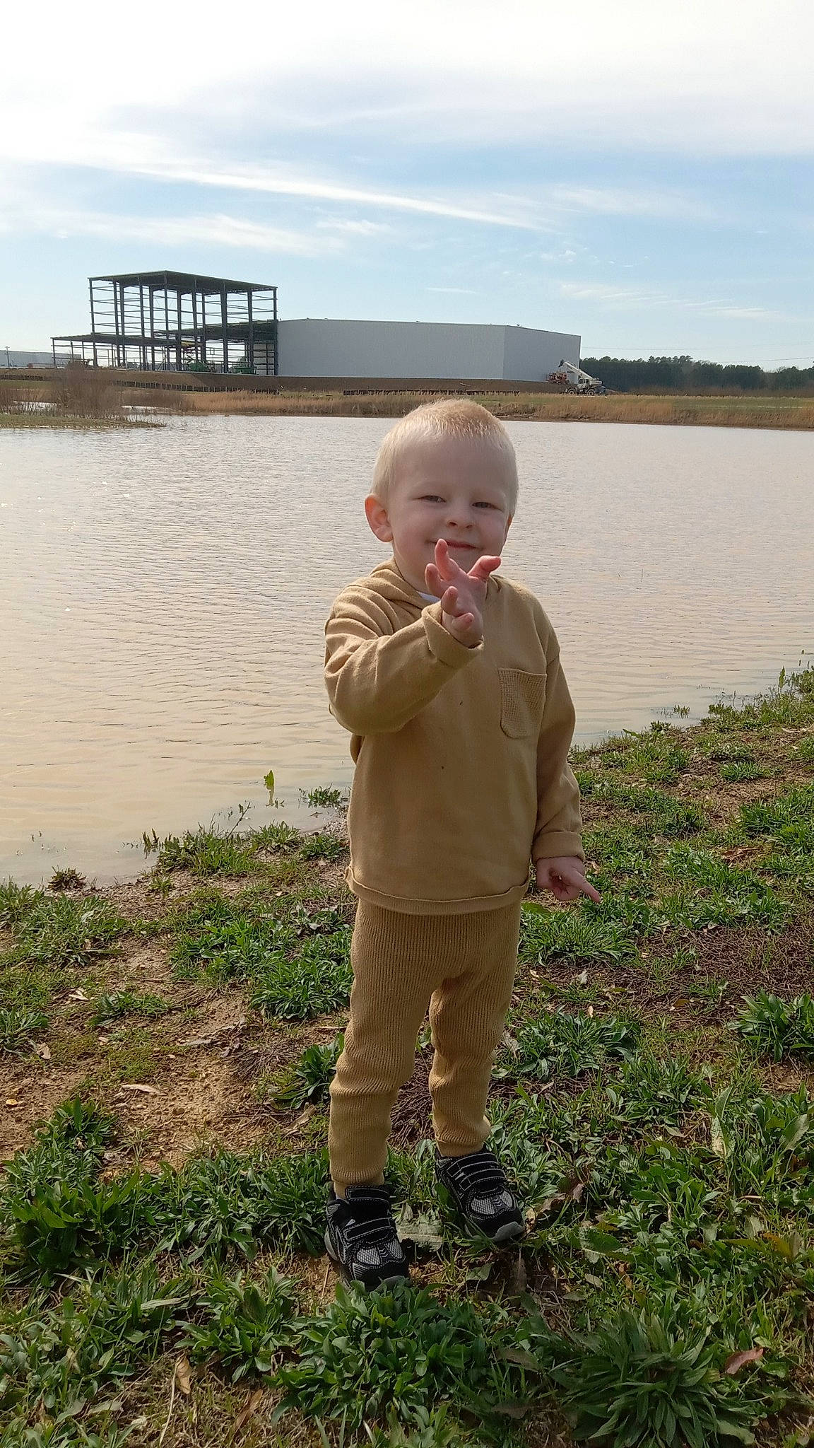 Waylon is registered to the contest to win money with this photo: baby, bank, child, cloud, fun, grass, grassland, happy, joy, lake, people_in_nature, person, reservoir, sky, smile, soil, standing, summer, toddler, vacation