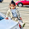 Gursher is registered to the contest to win money with this photo: child, kid, car, audi, parking_lot, jacket, sweater, camouflage_pants, rain_boots, top_knot, outdoor, daylight, person, casual, fashion, vehicle, parked_car, young, confident, urban