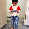 Gursher is registered to the contest to win money with this photo: child, boy, indoor, barefoot, carpet, jeans, turban, jacket, toy, handheld_device, playing, floor, doorframe, wall, concentration, casual_clothing, standing, young, person, technology