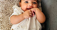 Tegh is registered to the contest to win money with this photo: baby, child, clothing, couch, cozy, cute, fabric, face, hand, happy, indoor, infant, person, pillow, playful, portrait, resting, smiling, soft_texture, striped