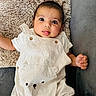 baby, infant, cute, tongue_out, striped_overall, bear_design, pillow, fluffy, white_clothing, short_sleeves, lying_down, cozy, gray_background, soft_texture, child, adorable, small_hands, portrait, indoors, happy