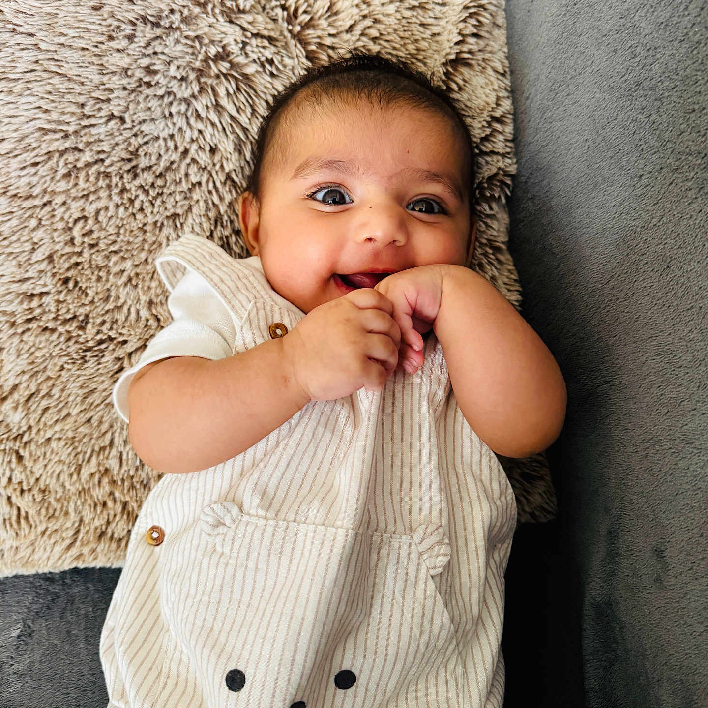 Tegh is registered to the contest to win money with this photo: baby, infant, smiling, cute, pillow, couch, striped_outfit, hand, face, happy, child, indoor, plush, cozy, young, person, portrait, clothing, relaxed, playful
