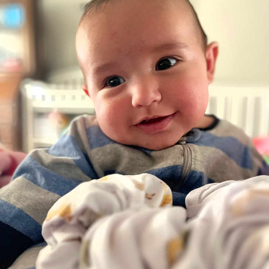 Cash King Caples joined the competition — help win amazing prizes! baby, infant, child, smiling, portrait, face, eyes, indoors, nursery, crib, blanket, clothing, striped_shirt, couch, soft_focus, close_up, happy, head, furniture, photograph