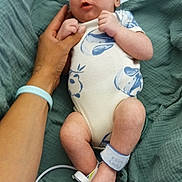 Abraxas joined the competition — help win amazing prizes! baby, infant, hand, blanket, onesie, hospital_band, foot, person, skin, sleeping_baby, newborn, clothing, bed, lying_down, wrinkled_blanket, human, cute, small, resting, indoors