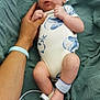 baby, infant, hand, blanket, onesie, hospital_band, foot, person, skin, sleeping_baby, newborn, clothing, bed, lying_down, wrinkled_blanket, human, cute, small, resting, indoors