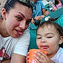 casual_clothing, child, crowd, event, family, fun, glasses, hair, hand, orange_cup, outdoor, people, seats, selfie, smile, spectators, stadium, toddler, tongue, woman