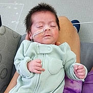 Sophia is registered to the contest to win money with this photo: baby, infant, onesie, nasal_tube, sleeping, person, hand, couch, fabric, clothing, home, indoor, lap, sleeve, face, hair, skin, medical, comfort, relaxation