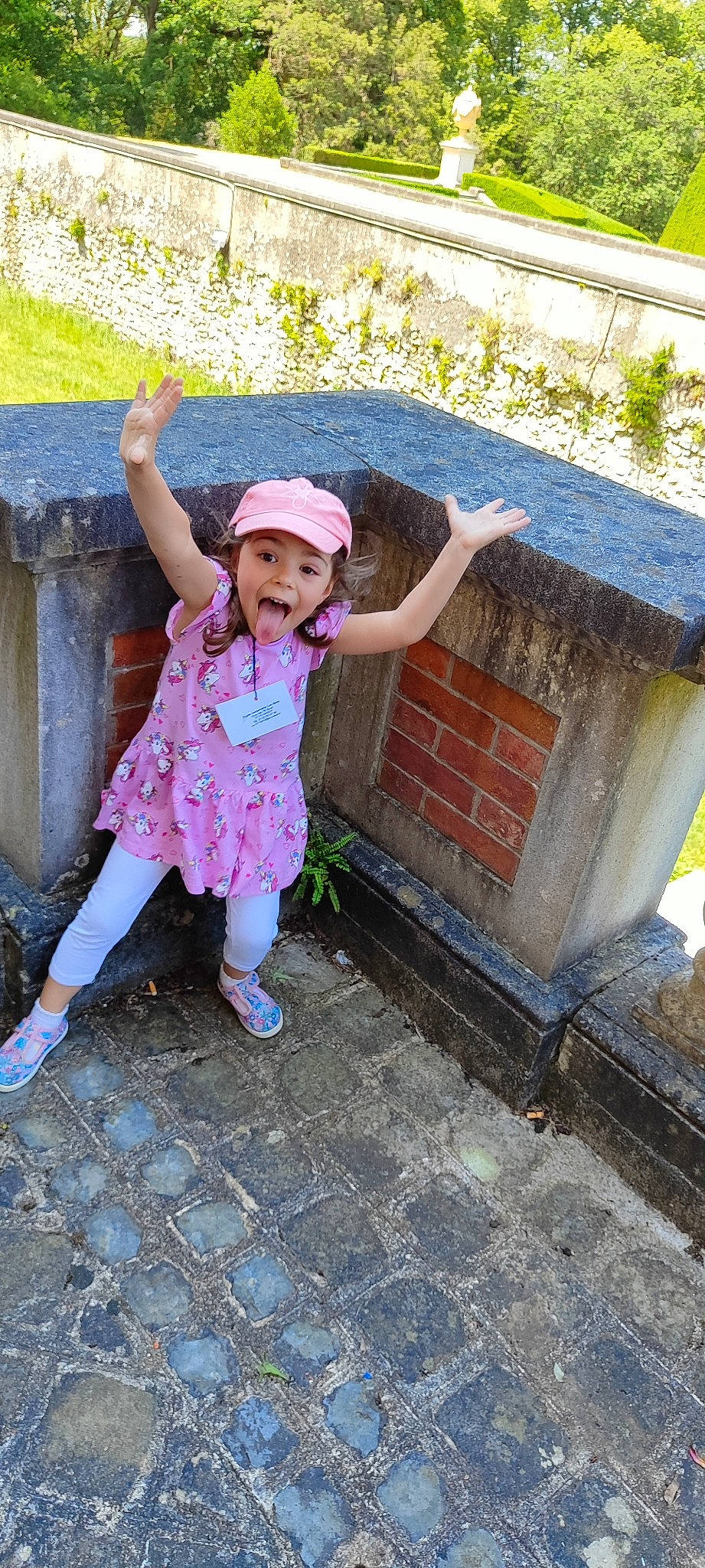 Lorena a rejoint le concours — aidez-le/la à gagner de superbes lots ! cap, child, concrete, fun, grass, happy, hat, headwear, human_leg, leisure, magenta, person, pink, play, sandal, sitting, smile, sun_hat, toddler, tourism