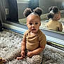 toddler, child, mirror, reflection, carpet, indoor, curly_hair, pigtails, leopard_print, pants, brown_shirt, sitting, barefoot, cute, expression, window, natural_light, room, wall, flooring