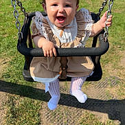 Nirvana joined the competition — help win amazing prizes! baby, child, swing, playground, grass, fence, sunlight, happy, smiling, toddler, outdoor, clothing, dress, lace, tights, toy, fun, person, nature, daytime