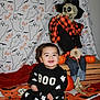Noel is registered to the contest to win money with this photo: baby, child, smiling, halloween, pumpkin, skeleton, costume, ghost_pattern, blanket, decor, festive, cute, indoor, person, holiday, orange, black_clothing, happy, sitting, toy