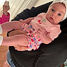 baby, child, person, indoor, holding, headband, pink_clothing, denim_shorts, hoodie, cookie, door, floor, wooden_floor, curious_expression, blue_eyes, shorts, hand, face, infant, casual_wear