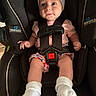 Ellie is registered to the contest to win money with this photo: baby, child, car_seat, infant, white_bow, pink_clothing, floral_shorts, white_socks, straps, black_car_seat, cute, portrait, indoors, sitting, person, young_child, headwear, smile, wide_eyes, safety_harness