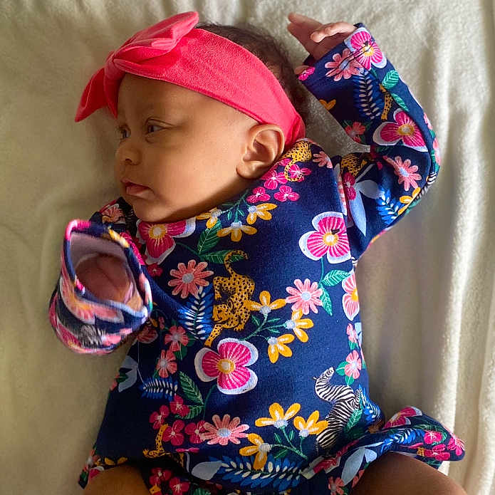 Nailah is registered to the contest to win money with this photo: accessories, baby, bed, bodypart, bonnet, cap, clothing, cushion, dress, face, finger, furniture, hat, head, headband, homedecor, newborn, person, photography, portrait