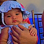 Elaine is registered to the contest to win money with this photo: baby, infant, child, hat, blue, floral, clothing, hand, adult, person, face, portrait, indoor, chair, skin, cute, holding, calm, soft_light, closeup