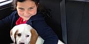 Marshmallow is registered to the contest to win money with this photo: black_hair, car, child, clothing, cuddle, cute, dog, friendship, headband, indoor, love, paper, pet, puppy, seat, seatbelt, smile, transportation, travel, window