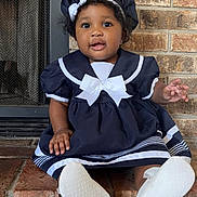Laysie is registered to the contest to win money with this photo: baby, child, sailor_outfit, hat, navy_blue, white_bow, brick_wall, fireplace, sitting, cute, smiling, indoors, portrait, footwear, white_shoes, curly_hair, infant, happy, person, young_child