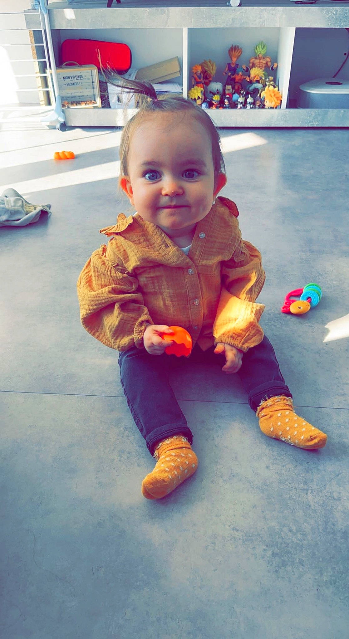 Mia a rejoint le concours — aidez-le/la à gagner de superbes lots ! baby, baby_toddler_clothing, cheek, child, floor, flooring, foot, fun, happy, human_body, joy, nose, orange, person, room, sitting, skin, smile, thumb, toddler