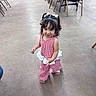 Amelia is registered to the contest to win money with this photo: toddler, child, girl, indoor, floor, concrete, pigtails, bows, red_and_white, checkered, outfit, ruffles, walking, smiling, chairs, tables, background, person, footwear, happy