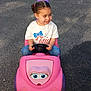 Izabella joined the competition — help win amazing prizes! child, toy_car, pink, steering_wheel, white_car, parking_lot, asphalt, playful, smiling, hair_tied, casual_clothing, outdoor, daylight, vehicle, small_vehicle, person, happy, young, girl, fun