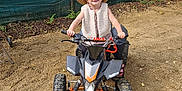 Alya participe au concours pour gagner de l'argent avec cette photo : atv, clothing, face, footwear, hat, head, machine, motorcycle, outdoors, person, photography, portrait, shoe, sitting, soil, spoke, sunhat, transportation, vehicle, wheel