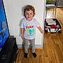 Alya participe au concours pour gagner de l'argent avec cette photo : california, chair, child, clothing, face, furniture, hair, indoor, plant, room, smile, socks, standing, suitcase, surf, television, toddler, tshirt, wall, wooden_floor