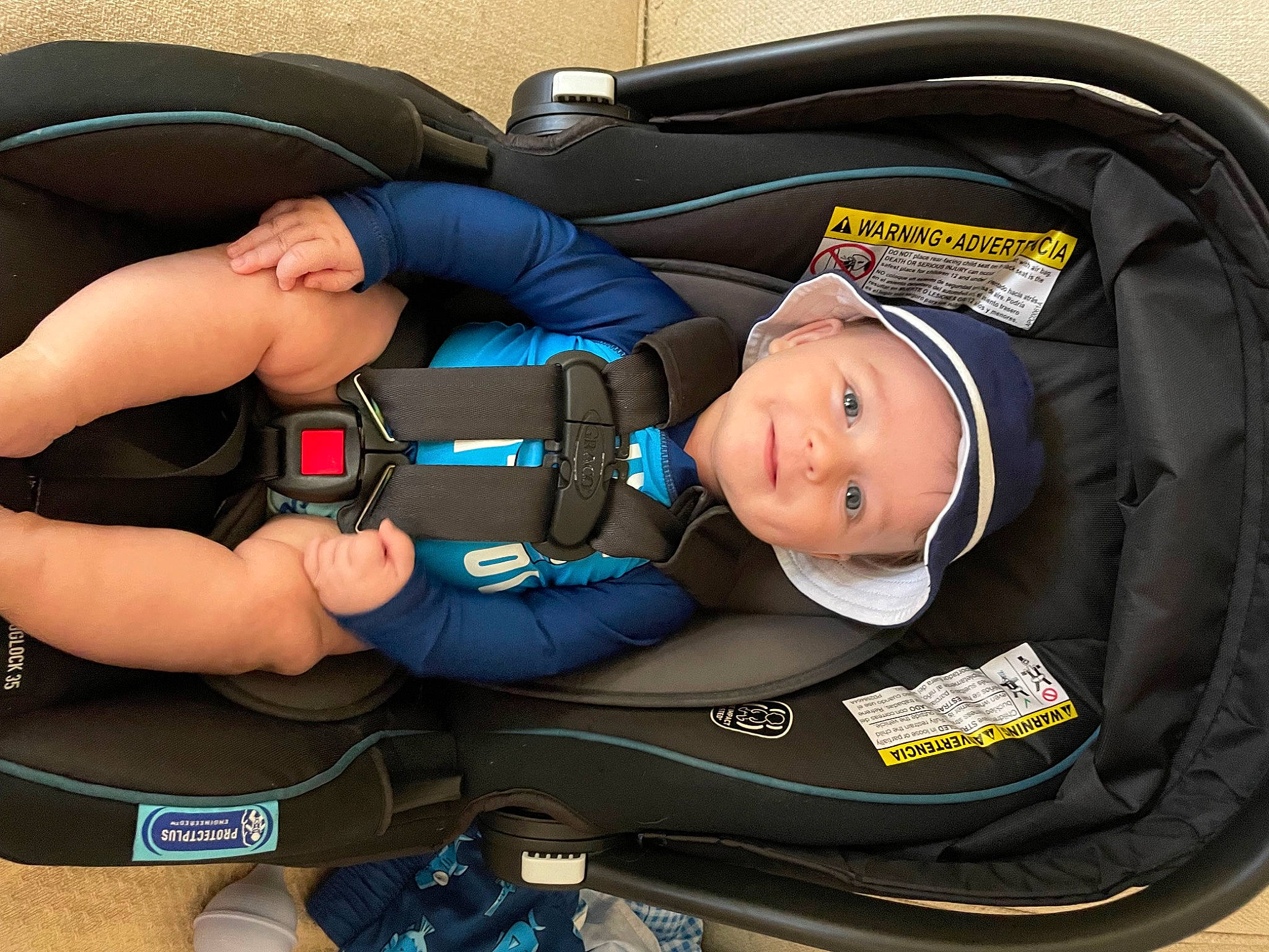 Elliot is registered to the contest to win money with this photo: auto_part, baby, baby_carriage, baby_in_car_seat, baby_products, baby_safety, baby_toddler_clothing, bag, blue, car_seat, child, comfort, electric_blue, fashion_accessory, headwear, joy, luggage_and_bags, person, plastic, service