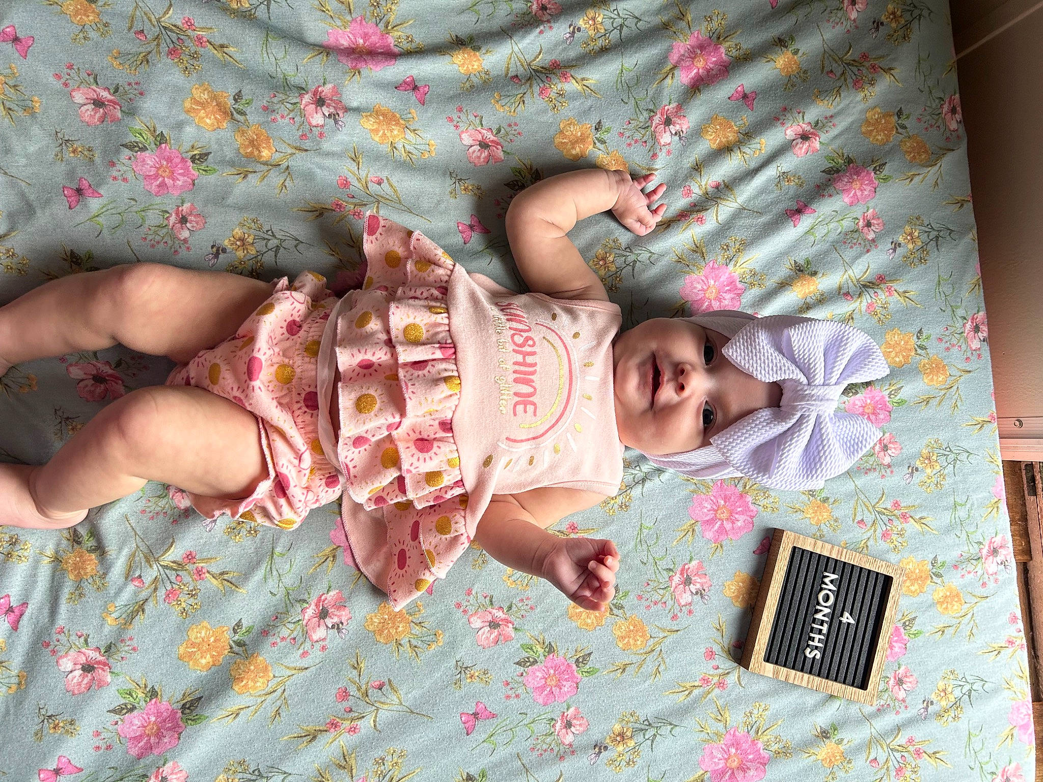 Everlee is registered to the contest to win money with this photo: baby, baby_products, baby_toddler_clothing, child, dress, foot, gesture, happy, headwear, human_leg, linens, nail, pattern, person, pink, room, skin, sleeve, thumb, toddler