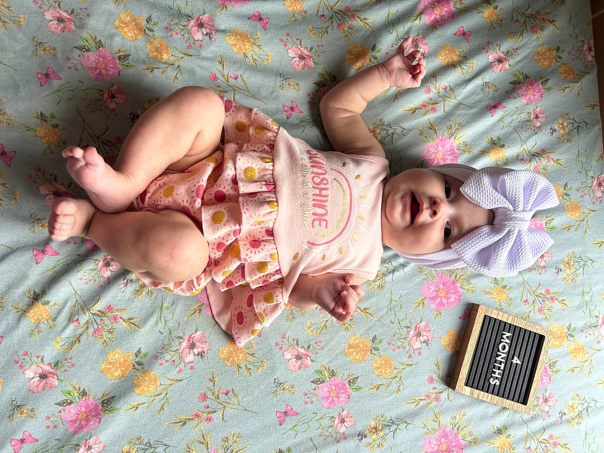 Everlee is registered to the contest to win money with this photo: abdomen, baby, baby_toddler_clothing, child, comfort, dress, foot, happy, head, headwear, human_leg, linens, pattern, person, pink, product, room, skin, textile, thigh