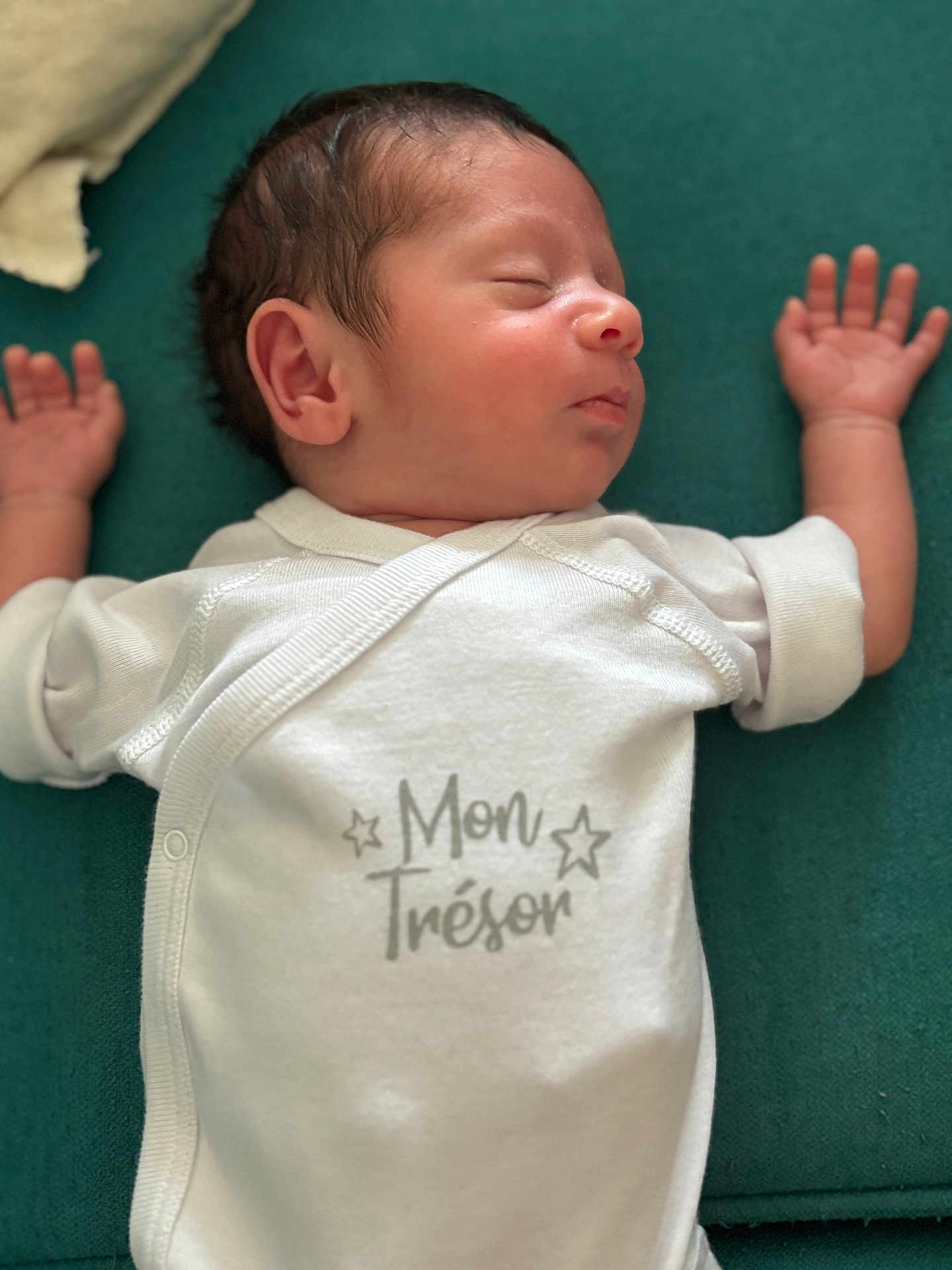 Milo a rejoint le concours — aidez-le/la à gagner de superbes lots ! newborn, baby, sleeping, onesie, white_clothing, infant, peaceful, cushion, green_background, face, hand, arm, head, skin, portrait, indoors, closeup, rest, child, soft_texture