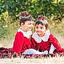 child, toddler, outdoor, grass, blanket, red_dress, white_collar, smile, happy, cute, hair_accessory, nature, siblings, playful, portrait, two_children, sitting, young_girls, daylight, warm