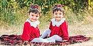 Elham is registered to the contest to win money with this photo: toddler, child, twins, red_dress, white_collar, hair_accessory, smiling, outdoor, grass, blanket, sitting, cute, portrait, happy, nature, female, young_child, playful, matching_outfits, daylight