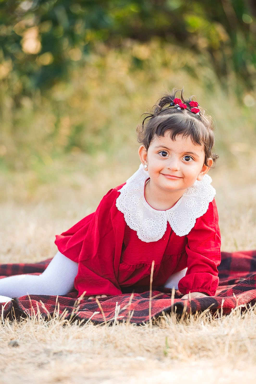 Elham joined the competition — help win amazing prizes! child, girl, red_dress, white_collar, outdoor, grass, blanket, smile, cute, portrait, young_child, earrings, hair_accessories, nature, playful, toddler, happy, face, daylight, posing