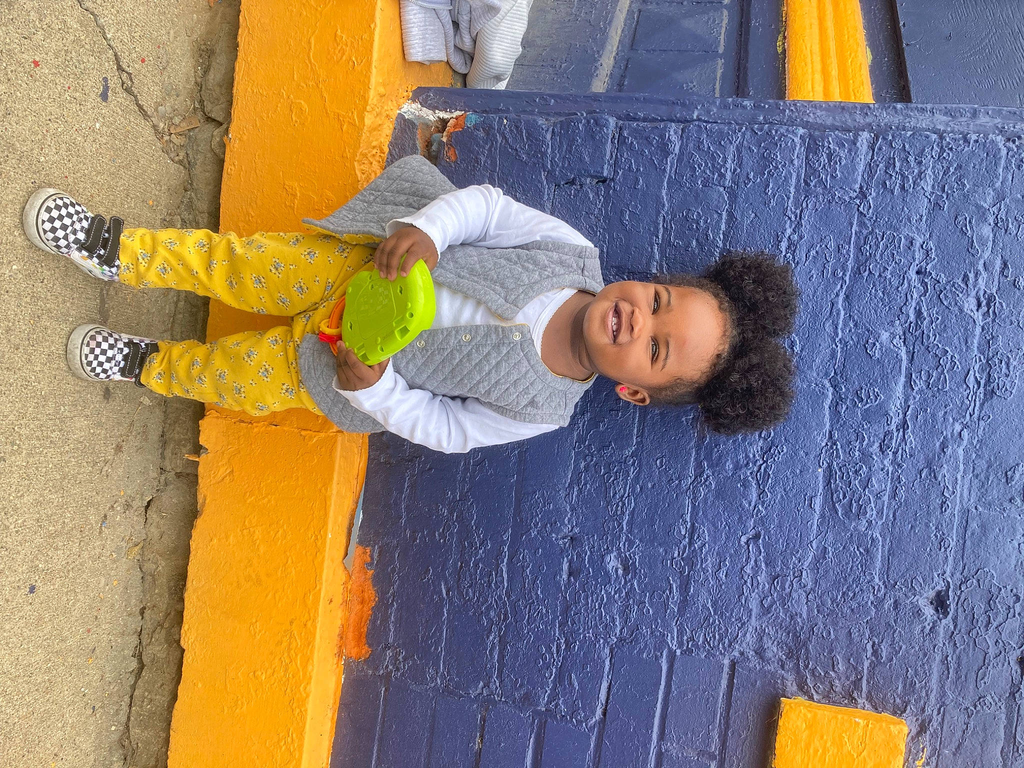 Zariah is registered to the contest to win money with this photo: asphalt, blue, child, concrete, denim, electric_blue, fun, human, joy, leisure, line, orange, person, road, road_surface, sidewalk, standing, street_fashion, toddler, wall