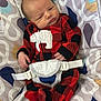baby, infant, onesie, red_clothing, black_clothing, polar_bear_patch, baby_seat, patterned_seat, straps, newborn, cute, small_hands, curious_expression, indoor, soft_fabric, child, person, seated, comfort, closeup