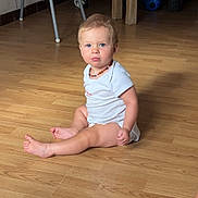 Axel participe au concours pour gagner de l'argent avec cette photo : toddler, child, baby, blue_eyes, sitting, wooden_floor, onesie, necklace, toy, indoor, furniture, table, chair, floor, person, portrait, expression, pout, home, cute