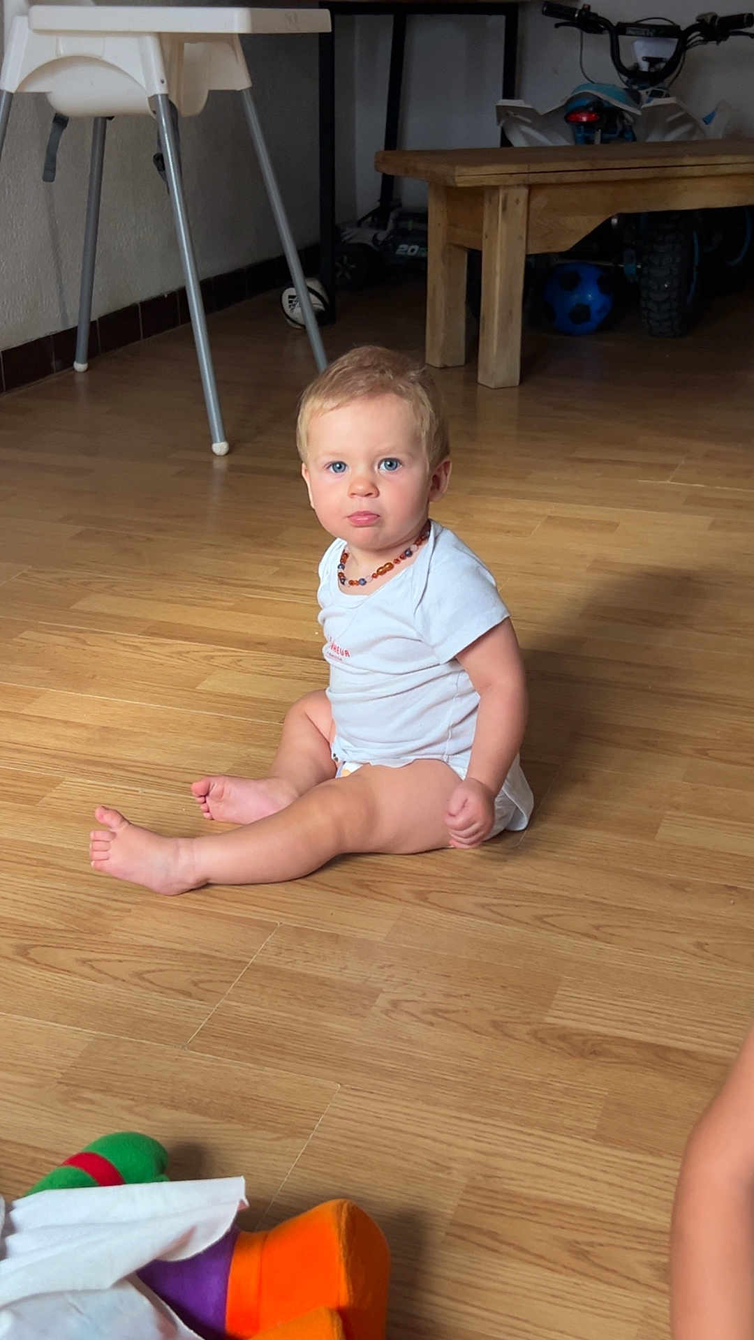 Axel participe au concours pour gagner de l'argent avec cette photo : toddler, child, baby, blue_eyes, sitting, wooden_floor, onesie, necklace, toy, indoor, furniture, table, chair, floor, person, portrait, expression, pout, home, cute