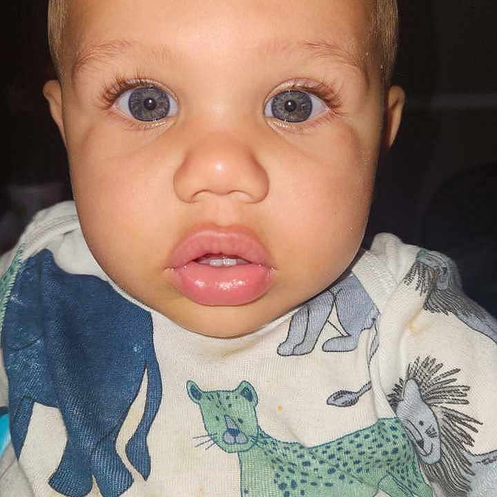 Marquis Junior is registered to the contest to win money with this photo: animal_print, baby, blue_eyes, child, close_up, clothing, curious, cute, expression, face, human, indoor, infant, onesie, person, plush_blanket, portrait, soft_lighting, toddler, young_child