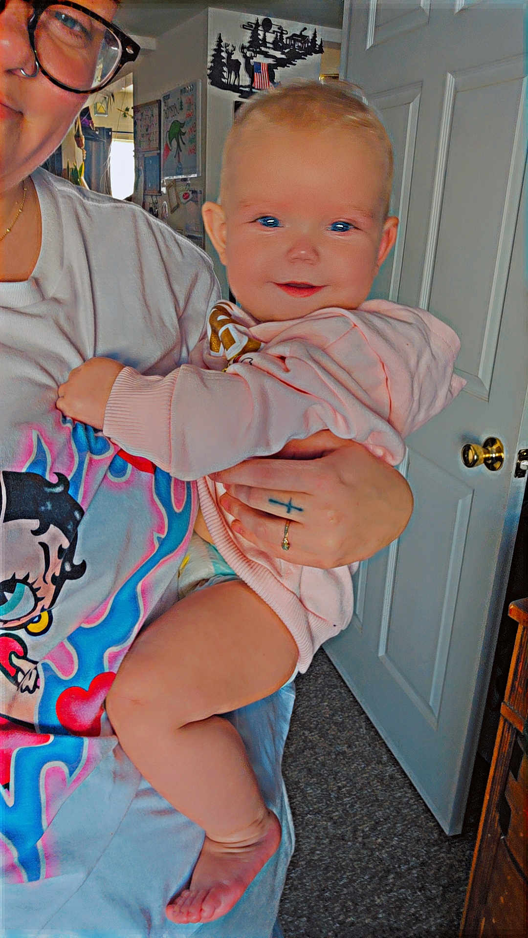 Lilyanna joined the competition — help win amazing prizes! baby, child, person, adult, glasses, tshirt, pink_hoodie, indoor, door, carpet, hand, tattoo, ring, smile, face, arm, leg, foot, wall_art, furniture